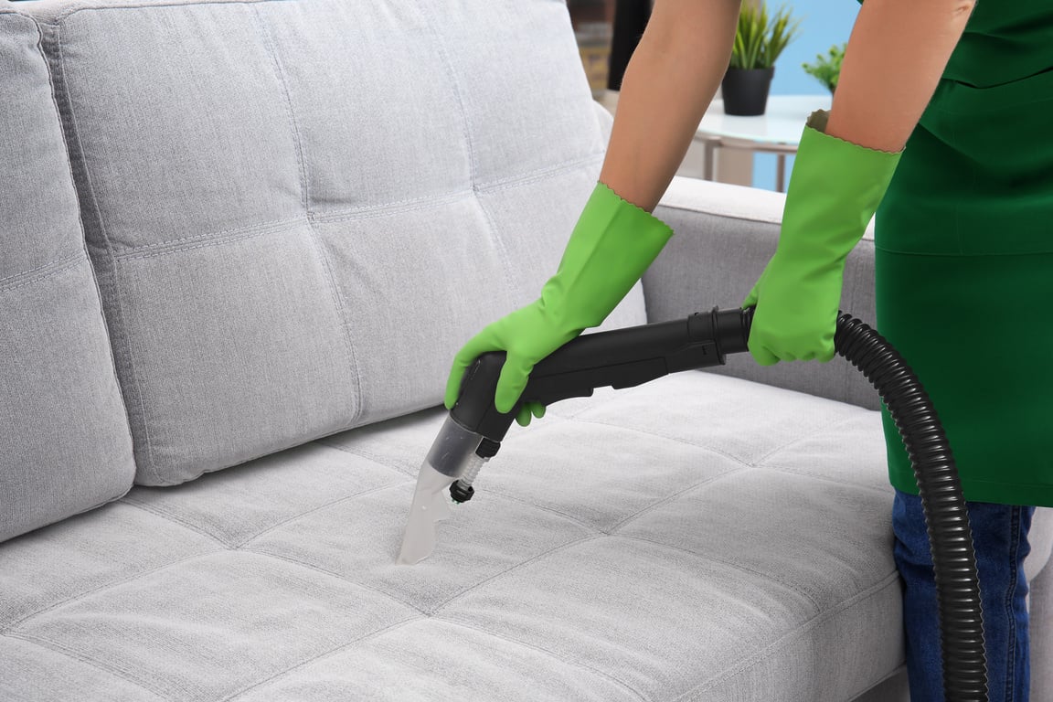 Woman Cleaning Couch with Vacuum Cleaner at Home